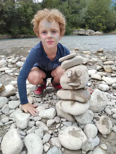Un garçon fait un cairn de pierres dans le lit d'une rivière